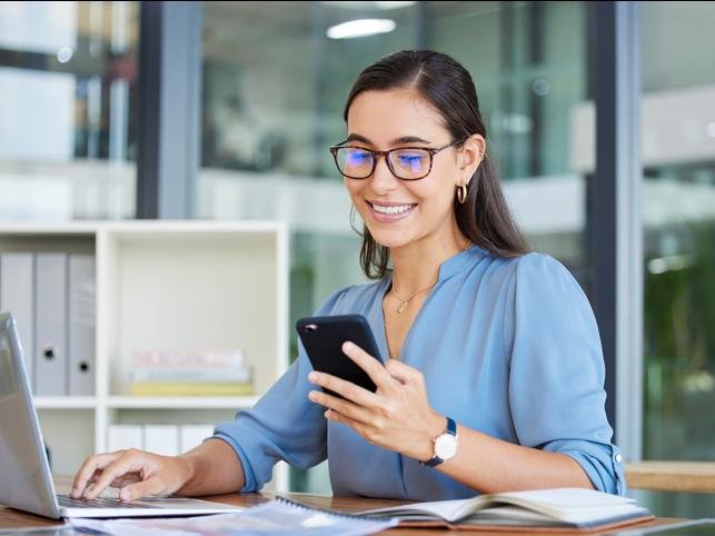 A woman smiles as she checks her phone