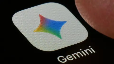 Getty Images A close-up shot of the Gemini application on a black screen. The icon is a white square with a four-point star in Google's colours, under which the word 'Gemini' is printed.