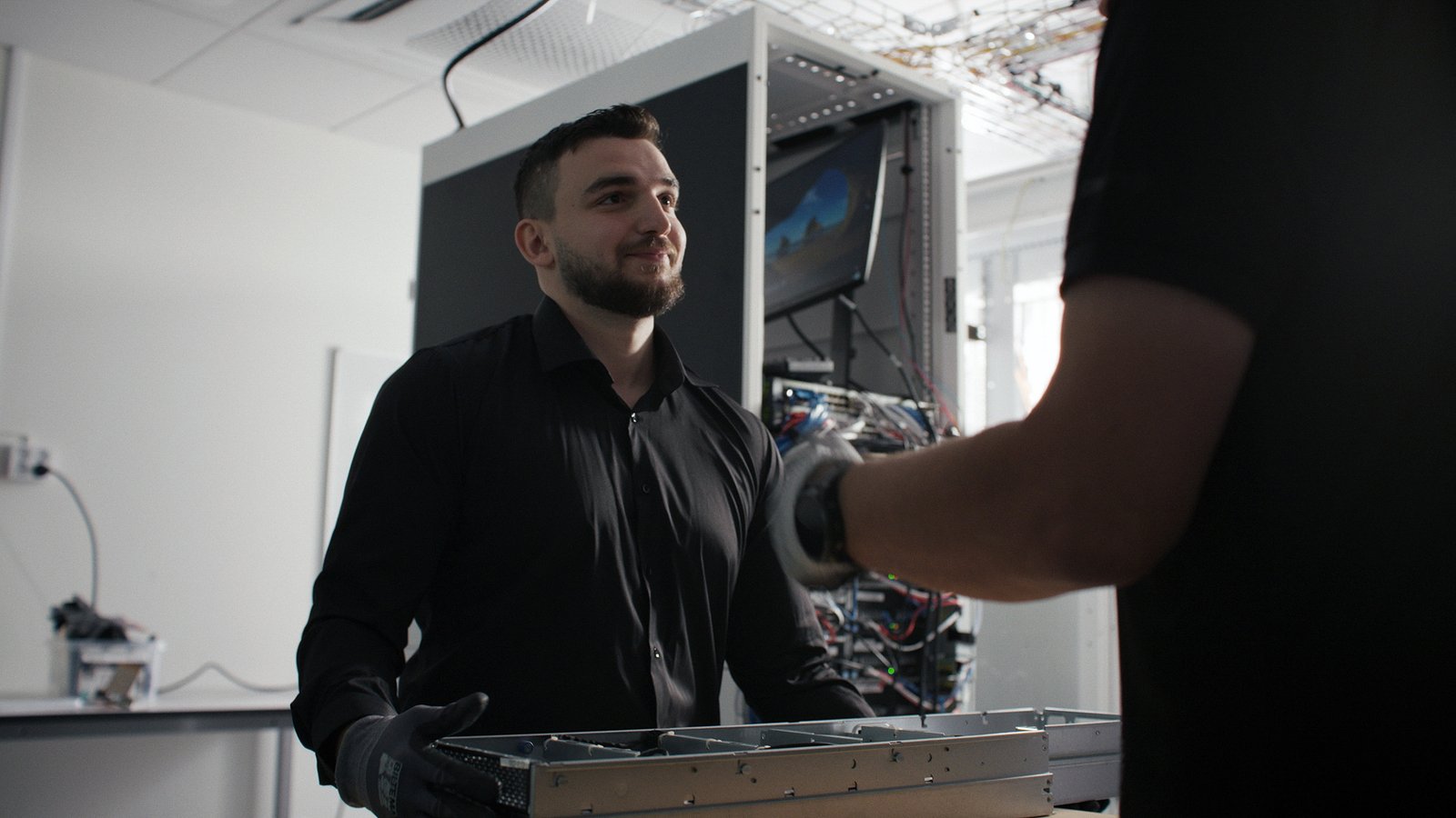 A young man with short dark hair and beard working in a datacenter.